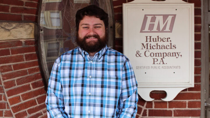 Professional public accountant standing in front of Huber Michaels & Company office.
