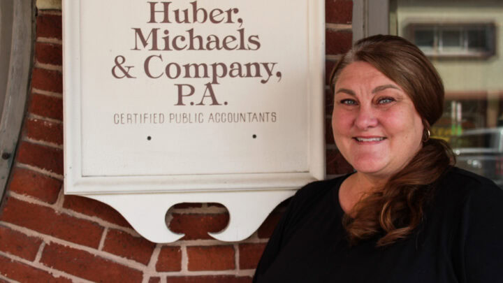 Highly skilled accountant woman standing next to Huber Michaels & Company sign in Pennsylvania.
